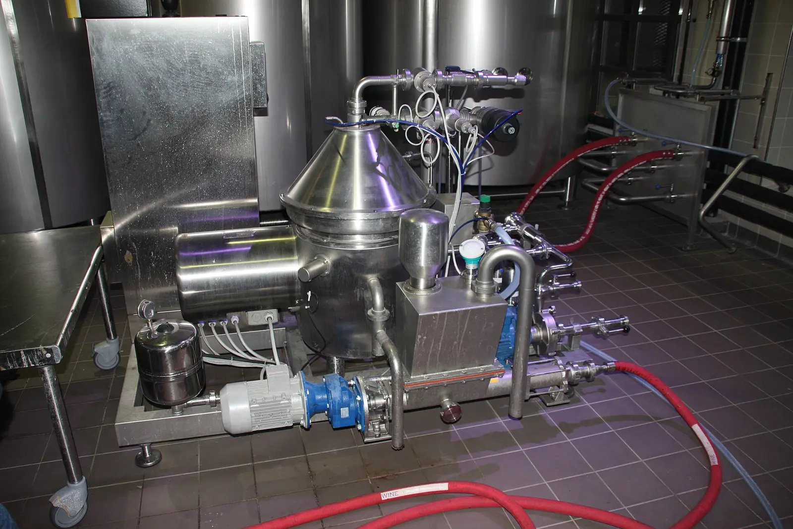 Disc stack separator centrifuge, a stainless steel vertical separator with its conical bowl hood and pipework on a skid in a brewery