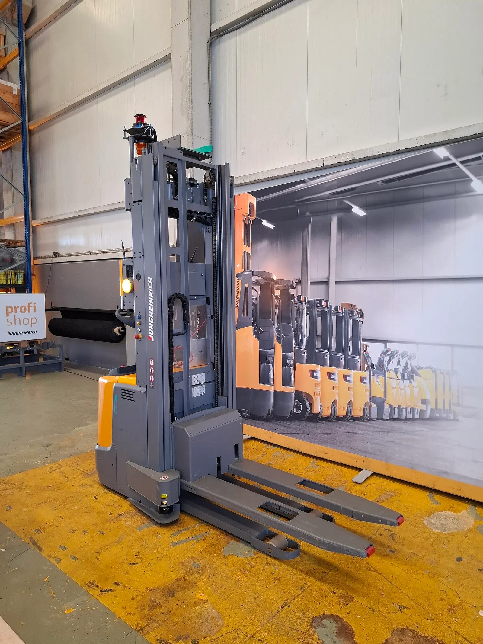 Electric pallet stacker, showing the battery body, tall lifting mast and pallet forks