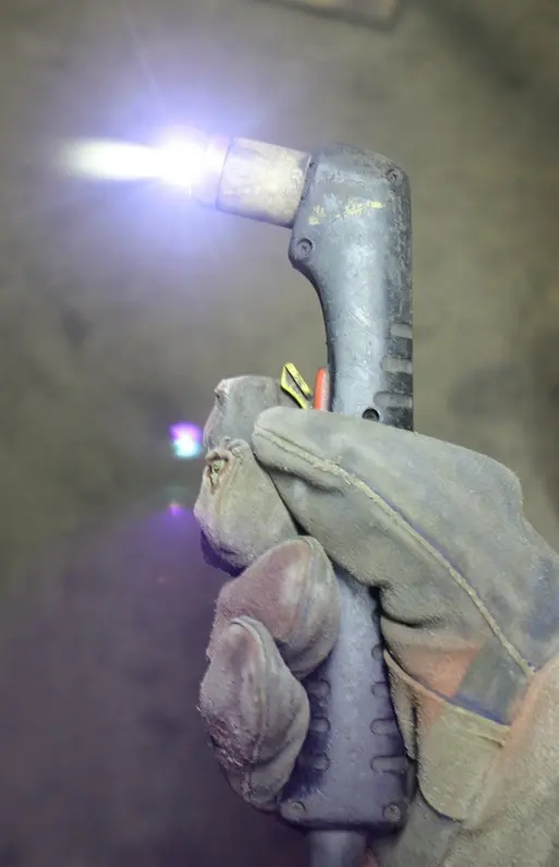 Hand-held plasma cutting torch in use