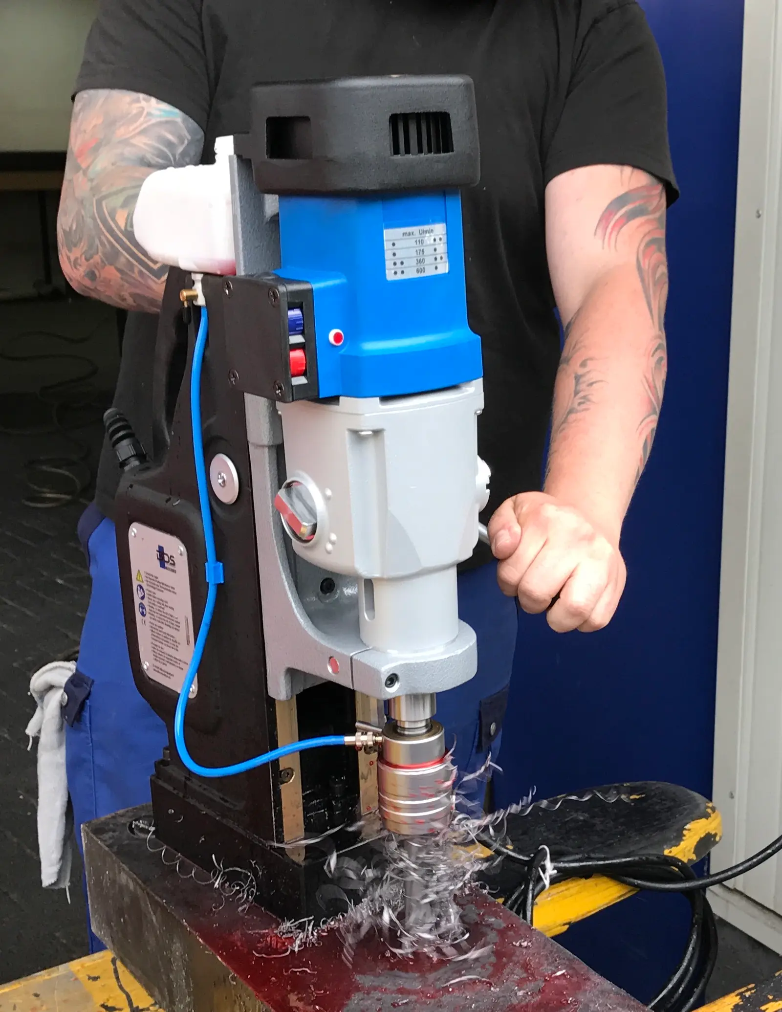 Magnetic core drilling machine, a blue-and-grey mag drill on its magnetic base cutting a hole in steel with an annular cutter