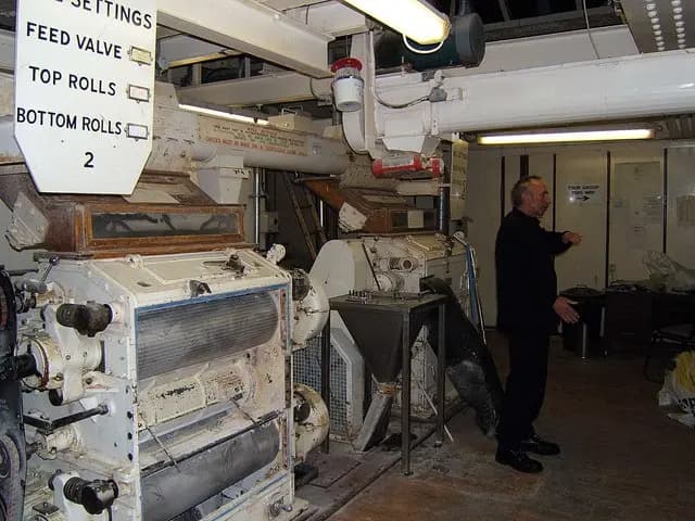 Malt roller mill, a multi-roll brewery grist mill with its roll housing open, feed hopper and roll-gap settings visible