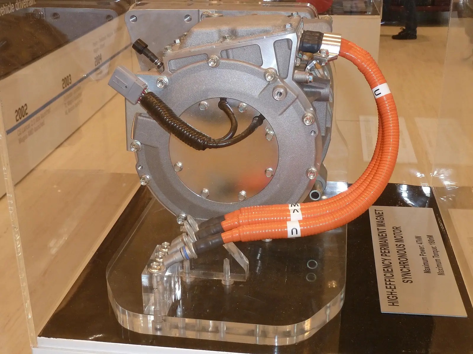 Permanent-magnet synchronous motor, a compact aluminium-housed motor with three-phase power cables on a display stand
