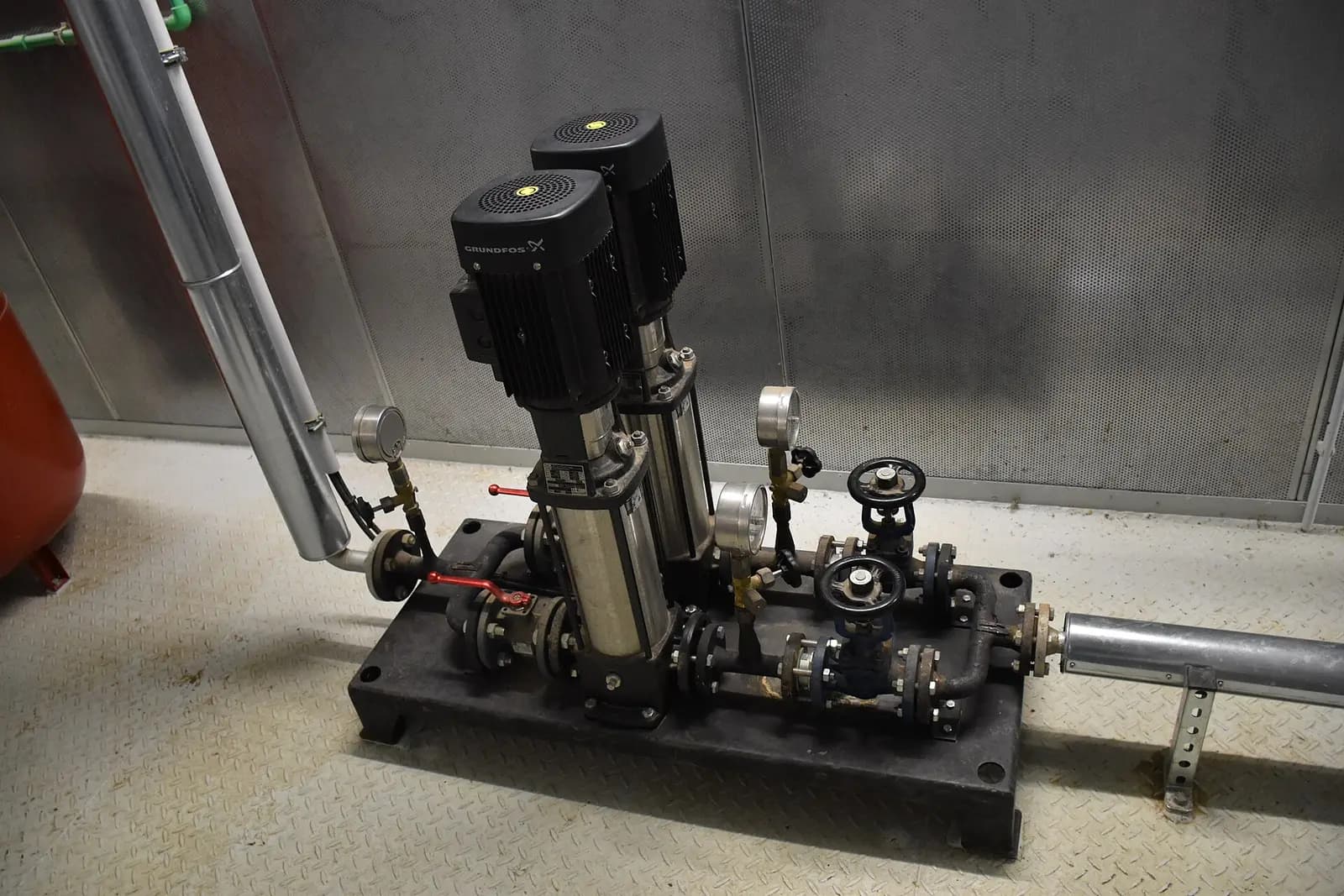 Vertical multistage centrifugal pumps, two in-line stainless-steel pumps with top-mounted motors on a booster skid with valves and gauges