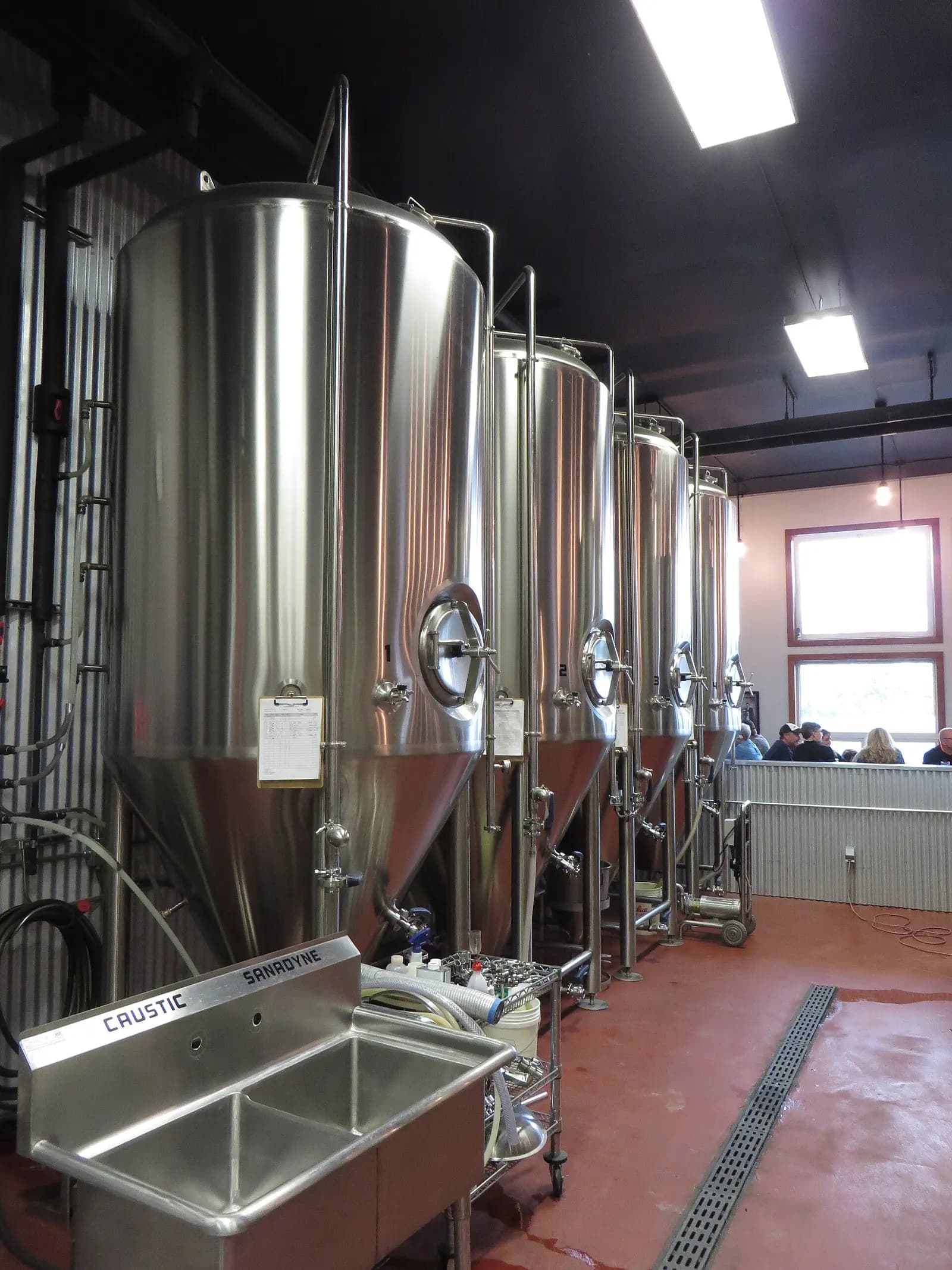 Jacketed stainless steel brewery vessel, a row of cylindroconical tanks with manways, sample valves and glycol jacket lines